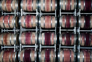 Barricas de vino ordenadas en racks metálicos dentro de una bodega de guarda con temperatura y humedad controladas